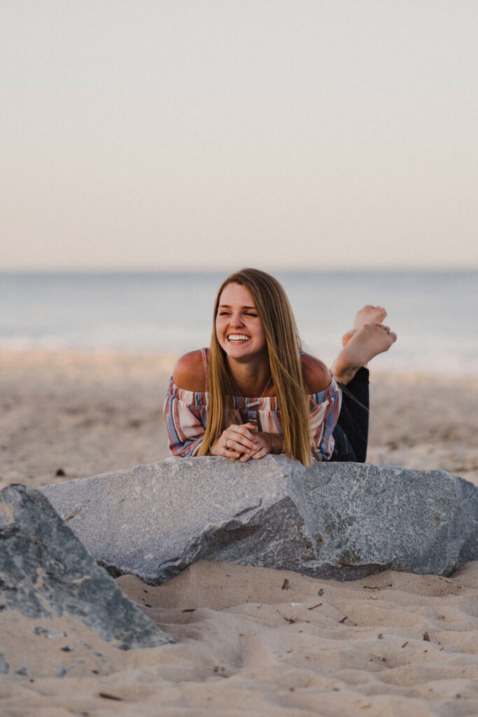 Girl smiling and laying on rock at Cape Henlopen State Park in Delaware